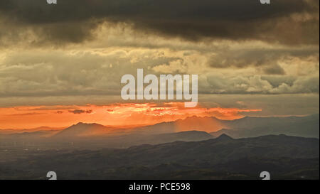 Calda bella alba con raggi di sole splendente giù per la montagna Foto Stock