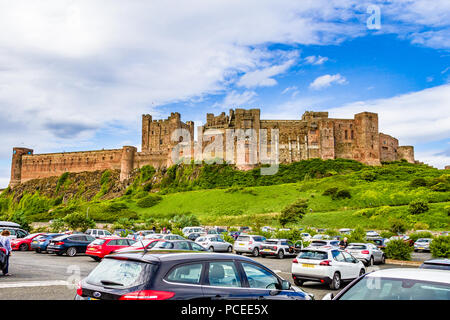 Occupato parcheggio auto sul bordo del piccolo villaggio di Bamburgh, rivolto verso il castello di Bamburgh, Northumberland, Regno Unito. Foto Stock