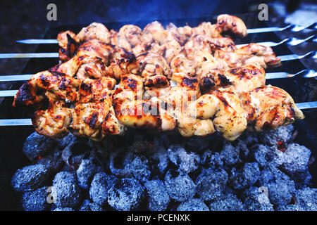 Gustosi spiedini di pollo. Spiedini di carne alla griglia aperta. Arrosti di carni cotte al barbecue con il fumo. Close up freschi barbecue durante la cottura. Foto Stock