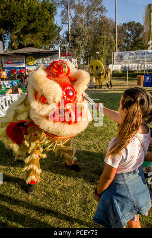 Un dollaro da una ragazza placates un costume drago cinese a una fontana Valley, CA, parco di divertimento. (Foto di Spencer Grant) Foto Stock