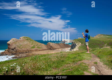 Cantabria, Costa Quebrada attorno a Playa El Madero beach, giovane uomo a scattare foto con il suo telefono cellulare Foto Stock