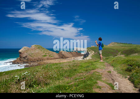 Cantabria, Costa Quebrada attorno a Playa El Madero beach, giovane uomo a scattare foto con il suo telefono cellulare Foto Stock