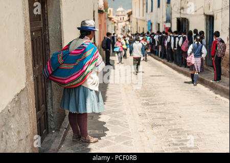 Gruppo di bambini voce alla scuola di mattina. Indossando i tradizionali colorati abbigliamento, camminando per la strada in uniformi di scuola in Cusco, Perù. Foto Stock