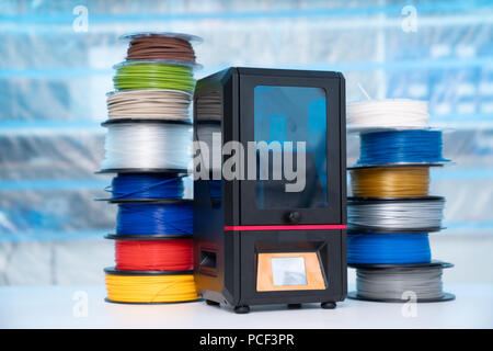 ABS e PLA filament accanto alla stampante 3D. Bobine di plastica Foto Stock