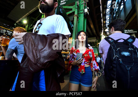 Turisti asiatici in un affollato mercato di Borough, Southwark, Londra, Inghilterra, Regno Unito.