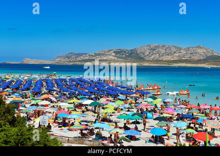 Affollata spiaggia con ombrelloni colorati e bagnanti a Stintino, Porto Torres, in Sardegna, Italia Foto Stock