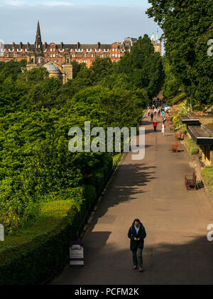 I giardini di Princes Street, Edimburgo, Scozia, Regno Unito, 1 agosto 2018. Delizioso caldo sole mattutino nel centro della città dei giardini. Vista attraverso il parco con la gente a piedi attraverso i giardini sul loro modo di lavorare Foto Stock