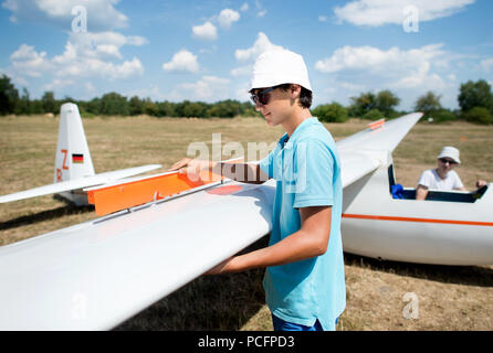 Burgdorf, Germania. Xxv Luglio, 2018. Marian Stojanovski (l) e Anton Mütz, giovani i piloti di parapendio di Burgdorf Air Sports Club, preparare un aliante per il decollo di un aeroporto vicino Ramlingen. Credito: Hauke-Christian Dittrich/dpa/Alamy Live News Foto Stock