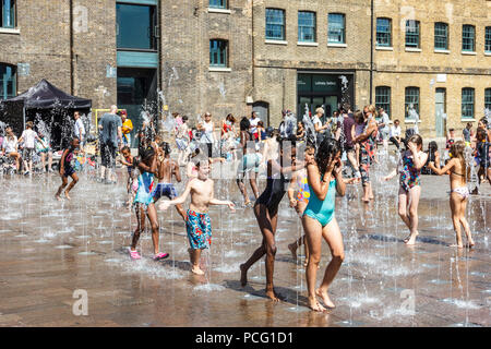 Famiglie e bambini si rinfrescano nelle fontane di Granary Square con l'aumento delle temperature, King's Cross, Londra, Regno Unito Foto Stock