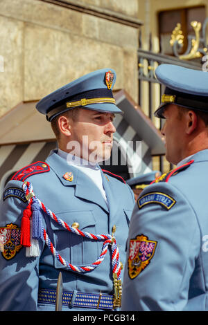 Un giovane uomo in divisa estiva con cappuccio sta formalmente al di fuori del Castello di Praga gates come parte del cambio della guardia del castello: Repubblica ceca. Foto Stock