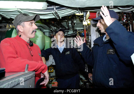 Petty Officer 1. Classe Jason Cook, il macchinista di mate e sottufficiali di 2a classe di Mark Cygnarowicz, macchinista di mate, assegnato al fast-attacco sommergibile USS Alessandria (SSN 757) spiegare la sub di sistemi di armi alla musica country star Aaron Tippin. Tippin ha girato il sommergibile prima di eseguire un concerto gratuito presso il Naval base sottomarina di New London come parte dello spirito di America Tour. Foto Stock