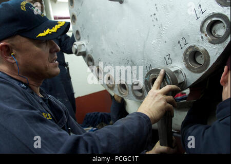 La Cmdr. Robert Bailey, chief engineer a bordo dell'assalto anfibio nave USS Bonhomme Richard (LHD 6), rimuove un bullone durante interventi di riparazione di una nave di caldaie durante una chiamata porta a Okinawa, Giappone. La nave è in rotta per alleviare la USS Essex (LHD 2) a Sasebo, Giappone. Foto Stock