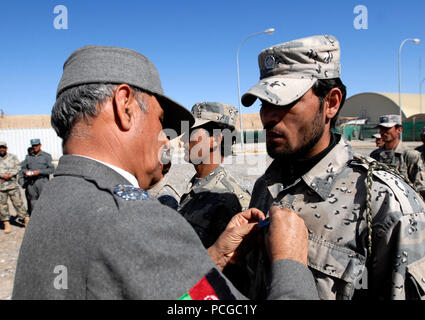 Provincia di Kandahar, Afghanistan (17 febbraio 2011) - Generale Zarefi pin sul rango del sergente junior alla frontiera afgana studente di polizia durante una graduazione da il sottufficiale (NCO) corsi a Spin Boldak, nella provincia di Kandahar, Afghanistan. Il corso NCO concentrarsi sulla leadership, la disciplina, la lotta contro il narcotraffico,contro le insurrezioni e piccole armi tattiche e dopo la laurea lo studente è stato promosso al rango di sergente junior. (US Navy Foto Stock