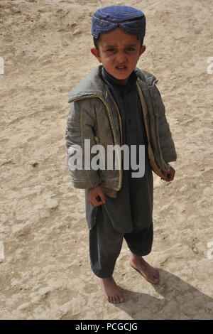 Ragazzo afghano orologi come coalizione di forze per le operazioni speciali soldati condurre una pattuglia smontati nel quartiere Latif, provincia di Ghazni, Afghanistan, Marzo 31. Smontate le pattuglie vengono utilizzati per coinvolgere enti locali afgani e di sviluppare un rapporto con i principali leader del settore. Foto Stock