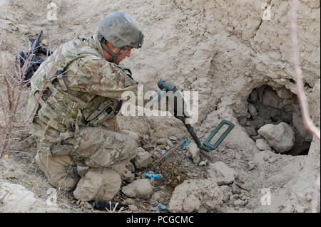 Un membro della coalizione di forze per le operazioni speciali utilizza un rivelatore di metalli per la ricerca di un sospetto di armi cache durante una pattuglia guidata da afghano di Polizia Locale in Walan Rabat village, Provincia di Zabul, Afghanistan, gen. 4. Foto Stock