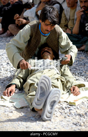 Un afghano di Polizia Locale candidato pratica facendo una medicazione compressiva a forze di coalizione sito nel distretto di Arghandab, provincia di Kandahar, Afghanistan, dal 15 ottobre 2012. I candidati sono sottoposti a tre settimane di corso che descrive le principali abilità di tiro, il pattugliamento esplosivi improvvisati il riconoscimento del dispositivo e le tecniche di sicurezza. L'ALP programma consente agli afgani di fornire protezione ai loro villaggi di origine e distretti. Foto Stock