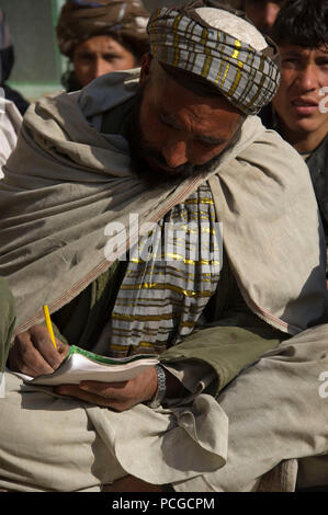 Un afghano di Polizia Locale candidato prende appunti durante un aiuto di prima classe nel quartiere Kajran, Daykundi provincia, Afghanistan, gen. 5. Le tre settimane di ALP corso descrive le principali procedure di polizia, armi di manipolazione e altre competenze necessarie per proteggere e difendere i cittadini afghani e mantenere la stabilità nella regione. Foto Stock