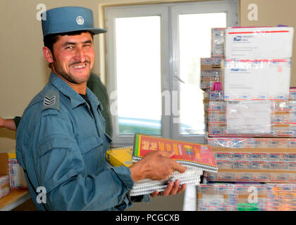 KABUL, Afghanistan - una nazionale afghano di ordine civile sergente di polizia aiuta a caricare le scatole di forniture scolastiche per essere distribuito in una scuola locale. Comando ANCOP Sgt. Il Mag. Abdul Wihad la punta di diamante della donazione di forniture scolastiche che ha luogo una volta al mese Foto Stock