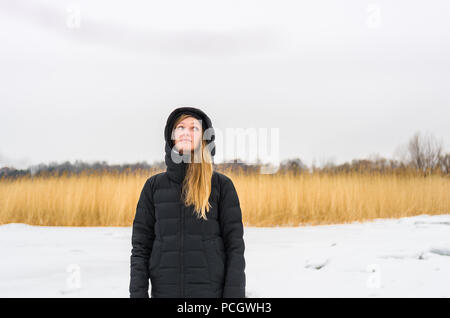 Reflective donna bionda in abbigliamento nero su uno sfondo inverno Foto Stock