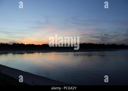 Tramonto su anatre nuotare sul serbatoio impoverito Foto Stock