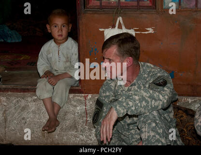 Un ragazzo afghano osserva un incontro tra Stati Uniti Esercito gen. Stanley McChrystal A., comandante della NATO la Forza internazionale di assistenza alla sicurezza e degli Stati Uniti Forces-Afghanistan, e gli anziani del villaggio. Foto Stock