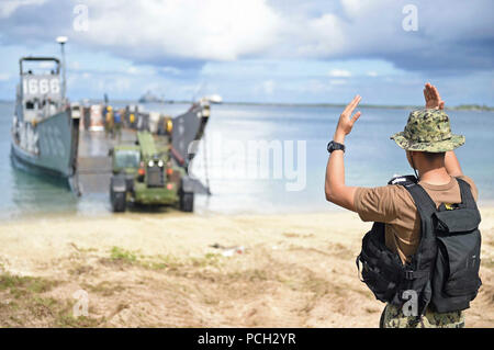 Riserva di spiaggia di artigianato, Guam (Agosto 10, 2015) da bombardieri Mate 3° di classe Jay Alberto segnali per un trattore di sbarcare Landing Craft Utility (LCU) 1666, assegnato alla spiaggia navale unità (NBU) 7, per consentire forniture e macchinari per essere caricati in ben coperta della amphibious dock landing ship USS Ashland (LSD 48) per i soccorsi in Saipan dopo il tifone Soudelor. Foto Stock