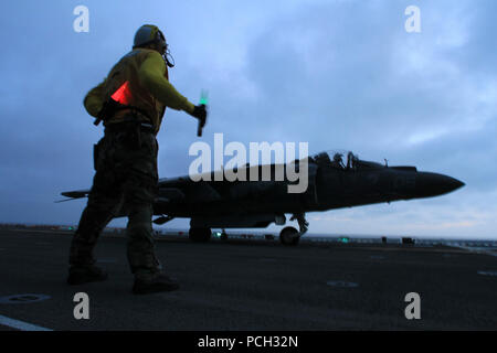 Oceano Pacifico (25 marzo 2013) un segnale di atterraggio guide arruolato un AV-8B Harrier assegnato al Marine squadrone di attacco (VMA) 214 durante le operazioni di volo a bordo di un assalto anfibio nave USS Boxer (LHD 4). Il Boxer è in corso di addestramento al largo della costa della California del Sud. Foto Stock