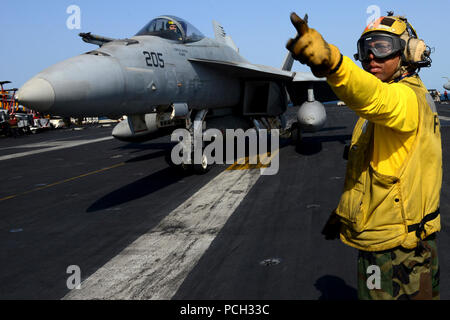Stati Uniti 5TH FLOTTA AREA DI RESPONSABILITÀ (GEN. 14, 2013) di aviazione di Boatswain Mate (manipolazione) 1a classe Brian Adams, da New York, dirige un'F/A-18E Super Hornet dal Tophatters di Strike Fighter Squadron (VFA) 14 a bordo della portaerei USS John C. Stennis (CVN 74). John C. Stennis è distribuito negli Stati Uniti Quinta Flotta area di responsabilità condurre le operazioni di sicurezza marittima, teatro la cooperazione in materia di sicurezza gli sforzi e le missioni di sostegno per l'Operazione Enduring Freedom. Foto Stock