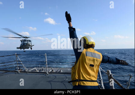 Oceano Pacifico (4 marzo 2013) Boatswain compagno del 3° di classe Brittany Chiles segnali per una SH-60B Mare Hawk elicottero mentre si atterra sul ponte di volo a bordo del Arleigh Burke-class guidato-missile destroyer USS McCampbell (DDG 85). McCampbell è parte del destroyer Squadron15, distribuito a Yokosuka, Giappone, ed è attualmente in corso di svolgimento esercizio puledro Eagle 2013 con nazione alleato per la Repubblica di Corea a sostegno della sicurezza regionale e la stabilità della regione Asia-Pacifico. Foto Stock