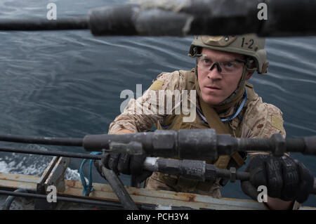 Un U.S. Marine assegnato al XIII Marine Expeditionary Unit imbarcato a bordo dell'assalto anfibio nave USS Boxer (LHD 4) salite a bordo del missile destroyer USS Mason (DDG 87) durante una visita, scheda, ricerca e sequestro esercizio Gen 12, 2014, nel Golfo di Oman. La Mason è stato implementato come parte di Harry Truman Carrier Strike gruppo a sostegno di le operazioni di sicurezza marittima e di teatro la cooperazione in materia di sicurezza gli sforzi negli Stati Uniti Quinta Flotta area di responsabilità. Foto Stock