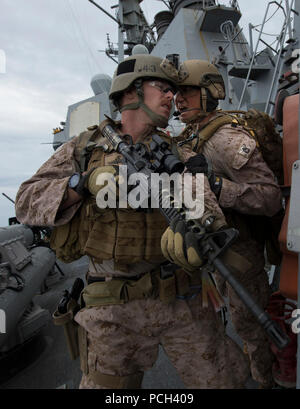 Un U.S. Marine, diritto, assegnato al XIII Marine Expeditionary Unit imbarcato a bordo dell'assalto anfibio nave USS Boxer (LHD 4) fornisce le istruzioni per un compagno di squadra durante una visita, scheda, ricerca e sequestro esercizio a bordo del missile destroyer USS Mason (DDG 87) Gen 12, 2014, nel Golfo di Oman. La Mason è stato implementato come parte di Harry Truman Carrier Strike gruppo a sostegno di le operazioni di sicurezza marittima e di teatro la cooperazione in materia di sicurezza gli sforzi negli Stati Uniti Quinta Flotta area di responsabilità. Foto Stock