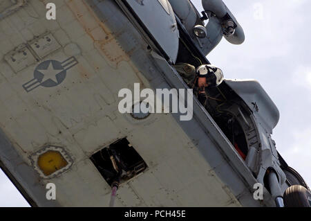 Un U.S. Navy naval air crewman controlla per vedere che un MH-60S Seahawk elicottero assegnato al mare in elicottero Combat Squadron (HSC) 23 è chiara del ponte di volo durante un rifornimento verticale tra militari di comando Sealift fast combattere la nave appoggio USNS Ponte (T-AOE 10) e dock anfibio sbarco nave USS Comstock (LSD 45) nel Golfo Persico, 17 maggio 2011. Comstock era sotto modo sostenere le operazioni di sicurezza marittima e di teatro la cooperazione in materia di sicurezza gli sforzi negli Stati Uniti Quinta Flotta area di responsabilità. Foto Stock