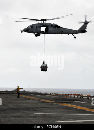 Un U.S. Sailor segnali ad un MH-60 Seahawk elicottero perché offre forniture sul ponte di volo a bordo di un assalto anfibio nave USS Boxer (LHD 4) durante un rifornimento verticale con la forza militare di comando Sealift flotta oliatore di rifornimento USNS Rappahannock (T-AO 204) nell'Oceano Pacifico il 17 marzo 2011. Boxer è sostenere le operazioni di sicurezza marittima e di teatro la cooperazione in materia di sicurezza gli sforzi negli Stati Uniti 7 flotta?s area di responsabilità. Foto Stock