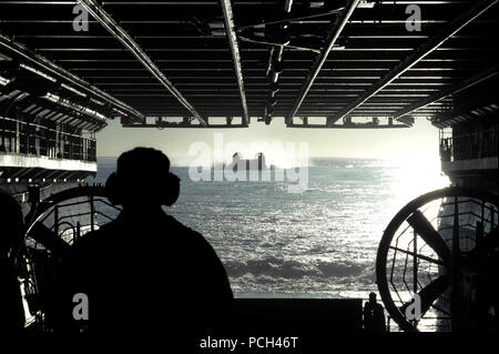 Un U.S. Sailor attende come una landing craft, cuscino d'aria si avvicina al ben coperta dell'assalto anfibio nave USS Makin Island (LHD 8) nell'Oceano Pacifico Gen 14, 2014. ( Foto Stock