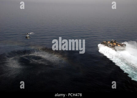 Stati Uniti 5TH FLOTTA AREA DI RESPONSABILITÀ (marzo. 29, 2013) UN UH-1Y Huey elicottero assegnato a mezzo marino Squadron (HMM) 364 (REIN) vola vicino a landing craft, cuscino d'aria (LCAC) durante la partecipazione a un esercizio con il trasporto anfibio dock nave USS Green Bay (LPD 20). è parte di Peleliu anfibio gruppo pronto e con elementi imbarcato del XV Marine Expeditionary Unit (15 MEU), è distribuito come supporto di le operazioni di sicurezza marittima e di teatro la cooperazione in materia di sicurezza gli sforzi negli Stati Uniti Quinta Flotta area di responsabilità. Foto Stock