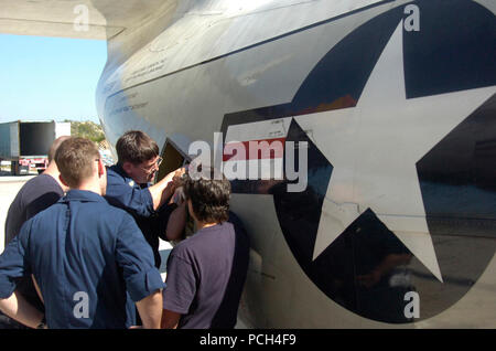 GUANTANAMO Bay a Cuba - Navy Chief Petty Officer Robert Hofman le riparazioni una rampa di bloccaggio staffa attuatore su un C-2 Greyhound vettore consegna a bordo degli aeromobili di Navy Airman Christopher Steffen, Navy Petty Officer di terza classe Josh Brennan e la marina Sottufficiali di terza classe Kristen McGarvey guardare agli Stati Uniti Stazione navale di Guantánamo Bay airfield, Gennaio 19, 2010. Il aviatori fanno parte della flotta squadrone logistica VRC-40 e sono impiegate nel supporto di funzionamento risposta unitaria, la fornitura di assistenza umanitaria ad Haiti. (JTF Guantanamo Foto Stock