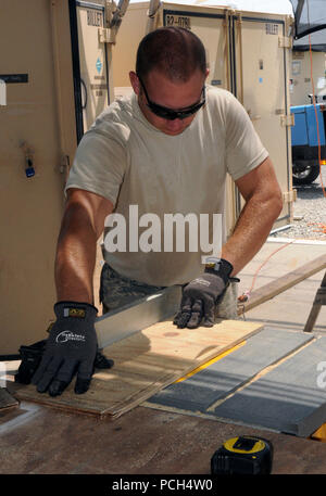 GUANTANAMO Bay a Cuba - Air Force Staff Sgt. Gary Learmonth, della 474th Expeditionary Ingegneria Civile Squadron, Base di emergenza forza ingegnere, Joint Task Force Guantanamo, misure di un pezzo di legno compensato prima di iniziare il ciclo di sezionatura in Camp giustizia, 16 marzo 2010. Il 474th ECES mantiene la Expeditionary complesso giuridico, di vitale importanza per la JTF missione. JTF Guantanamo conduce al sicuro, umano, legale e trasparente di cura e custodia dei detenuti, compresi quelli condannati dalla commissione militare e quelli ordinati rilasciato da un tribunale. La JTF conduce la raccolta di intelligence, analisi e diffusione per la protezione Foto Stock