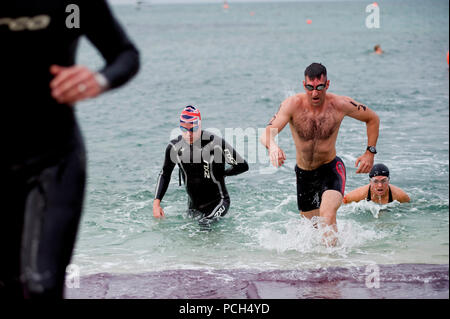 Il Mag. Stephen Mossour, destra, assegnato a U.S. Forze Navali del comando centrale, Navale attività di sostegno il Bahrein, completa la prima gamba dell'Alba Olympic Triathlon di Alba. Più di venti membri del servizio hanno gareggiato per il locale ha ospitato il triathlon, che consisteva di un 5K nuotare, 40K in bici, e 10K l'esecuzione. Foto Stock