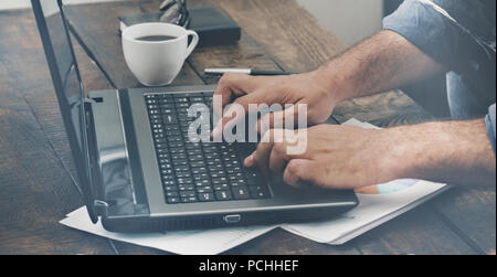 Mani maschio digitando il testo su la tastiera del laptop close up Foto Stock