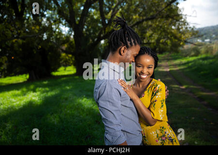 Giovane abbracciando e sorridente in un parco Foto Stock