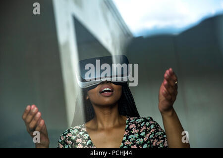 Donna africana guardando attraverso le cuffie VR Foto Stock