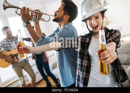 Gruppo di amici a suonare la chitarra e di festa a casa Foto Stock