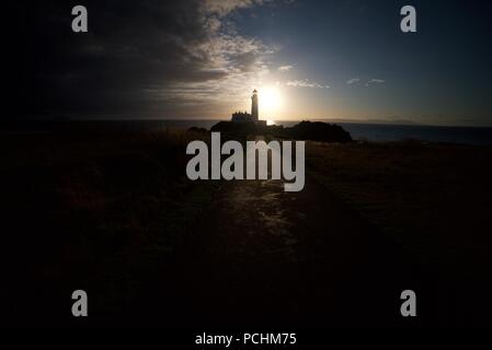 Silhouette di un faro (Turnberry Faro) lungo la costa dell'Ayrshire accanto al Trump Turnberry Golf, con il tramonto in background. Foto Stock