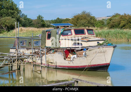 Trascurato vecchia barca di legno con foro e marciume legno ormeggiata presso un pontone galleggiante sul Fiume Arun in Arundel, West Sussex, in Inghilterra, Regno Unito. Foto Stock