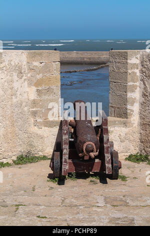 Ex fortezza Portoghese sulla costa dell'Oceano Atlantico a El Jadida, Marocco. Cannone storico nella finestra del muro di pietra. Azzurro cielo. Foto Stock