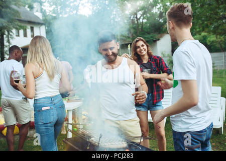 Gruppo di amici fare barbecue nel cortile. concetto circa il bene e stato d'animo positivo con gli amici Foto Stock