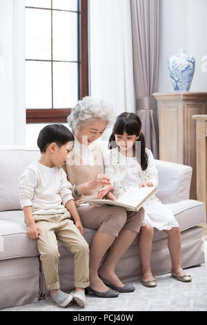 Allegro nonna cinese e i nipoti guardando album di foto Foto Stock