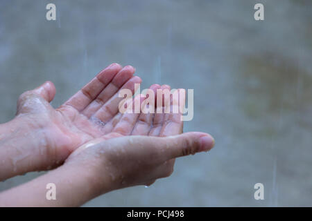 Close up della donna di mettere la mano sotto la pioggia la cattura di gocce di pioggia, il concetto di acqua. Foto Stock