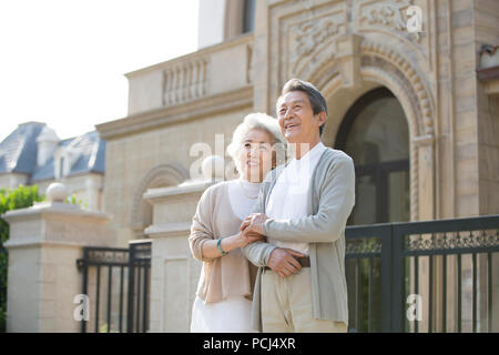 Allegro senior coppia cinese in piedi di fronte a loro villa Foto Stock