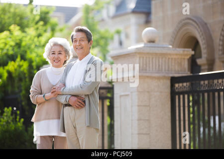 Allegro senior coppia cinese in piedi di fronte a loro villa Foto Stock